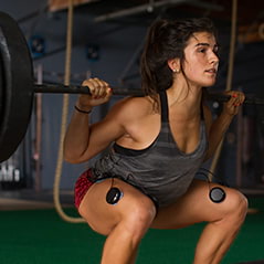 A woman wearing Compex electrodes while lifting weights